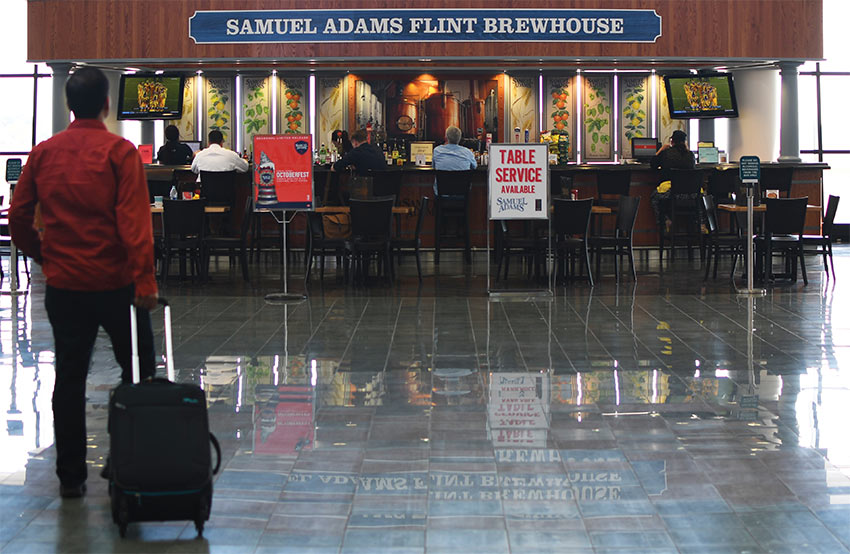 A man approaching the Samual Adams Flint Brewhouse bar with about 20 seats at the bar.
