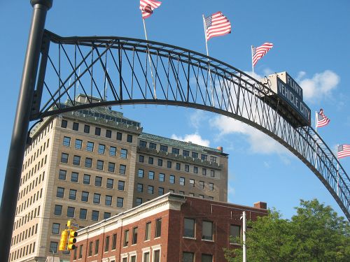 The image is on the Flint vehicle city sign with American flags with buildings behind.  