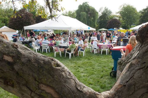 The image is of a group of people sitting under party tents at the taste in Fenton event. 